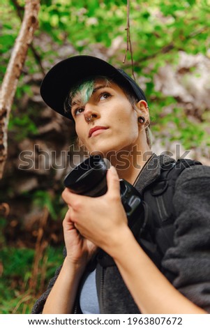 young photographer holding a photo camera and observing his surroundings in the forest. girl enjoying a nature day. Activities in the natural environment.