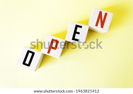 the word open is composed of square wooden cubes with letters on a yellow background.