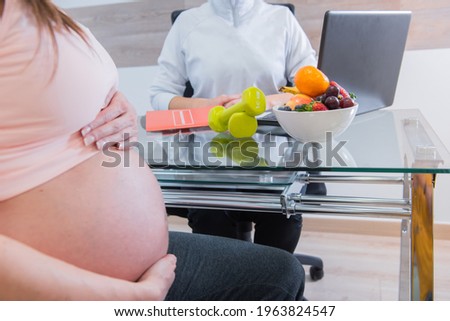 pregnant at the doctor's office. pregnant sitting on a chair in front of the nutritionist doctor Royalty-Free Stock Photo #1963824547