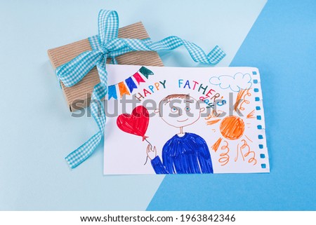 Happy Fathers Day. Childs drawing of her dad and gift a blue minimal background.