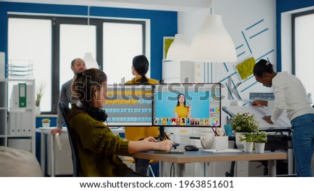 Professional woman retoucher edits assets in creative media agency office working with diverse team. Content creator doing portrait retouching with photo editing software in digital multimedia company