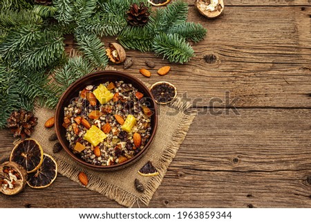 Traditional Christmas dish Kutya. Slavic sweet food with dried fruits, poppy seed and nuts. Wheat porridge in East European, Russian, Ukrainian countries. Old wooden boards background, top view