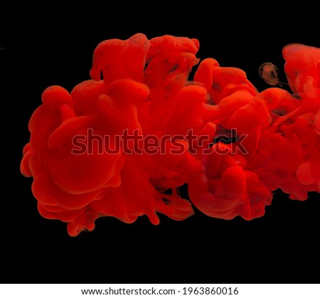 explosion of acrylic red paint in clear water. Black background. copy space.