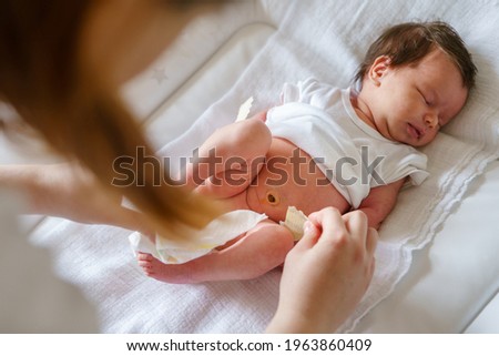 Top view on caucasian baby sleep while her mother is changing diapers and clothes newborn lying on the bed at home - parenting childhood new life and growing up concept Royalty-Free Stock Photo #1963860409