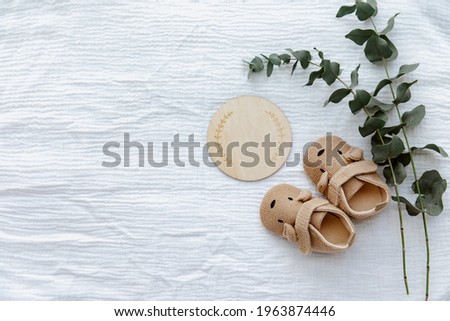 Newborn booties with empty card and wooden toys. Baby Background, top view, flat lay, copy space 