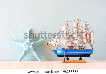 decorative boat and seashell over wooden textured background.