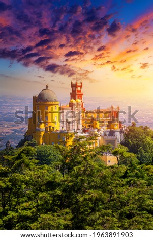 Famous historic Pena palace part of cultural site of Sintra against sunset sky in Portugal. Panoramic View Of Pena Palace, Sintra, Portugal. Pena National Palace at sunset, Sintra, Portugal.  Royalty-Free Stock Photo #1963891903