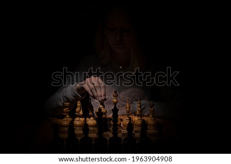 girl in the shadows plays vintage chess on a dark background. old chess. business concept.