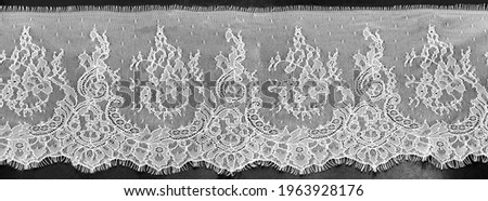 Gray-white lace on a black background. Template for wedding invitation and greeting card with lace fabric background. Filigree floral elements, ornate vintage ornament.