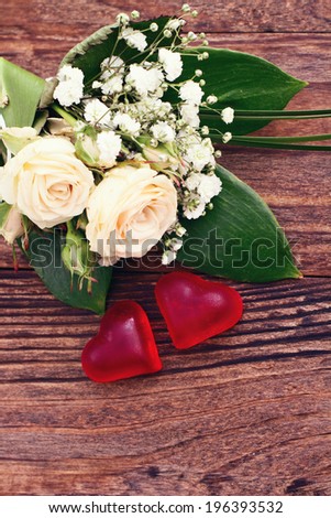 Flowering branch with white delicate flowers on wooden surface. Wedding rings. Wedding bouquet, background. 