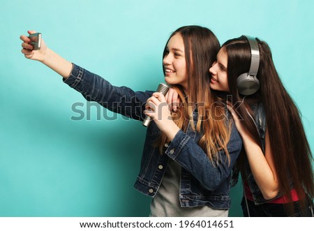 lifestyle, happiness, emotional and people concept: beauty hipster teenagers with a microphone singing and take picture with smartphone