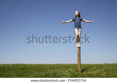 Young girl balancing outdoors on a trunk of a tree