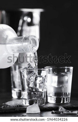 Cold Vodka in shot glasses on black background, ready to drink 