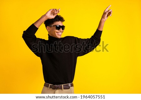 Photo of sweet cool dark skin man wear black jumper eyewear dancing pointing empty space isolated yellow color background