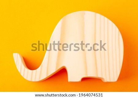 Elephant figurine carved from solid pine by hand jigsaw. On a yellow background.