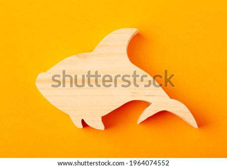 Figurine of a shark carved from solid pine by hand jigsaw. On a yellow background.