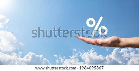 Male hand holding interest rate percent icon on blue sky background. Interest rate financial and mortgage rates concept.Banner with copy space.
