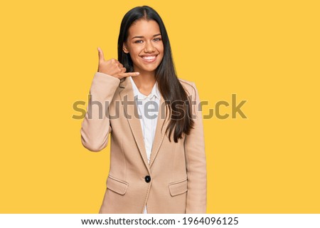 Beautiful hispanic woman wearing business jacket smiling doing phone gesture with hand and fingers like talking on the telephone. communicating concepts. 