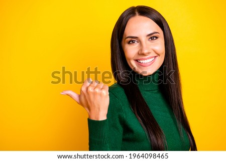 Photo of young charming positive pretty girl point thumb copyspace advertisement isolated on yellow color background