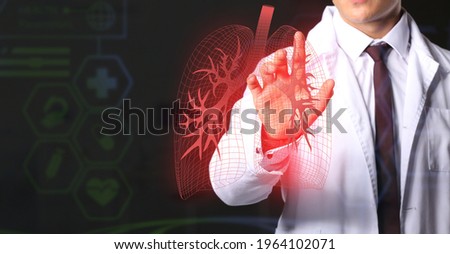 Male doctor using virtual screen with picture of lungs on dark background
