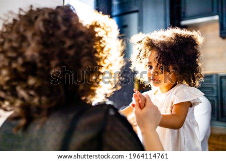 curly hair cute little mixed race baby in mothers hands in cozy room daylight