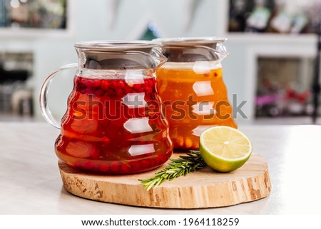 two teapots with aromatic tea, sea buckthorn-citrus and berry-flower. Both teapots stand on a wooden lime stand