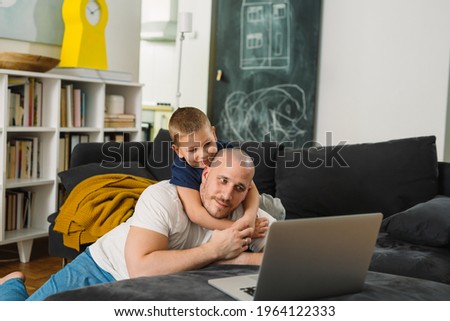 father using laptop computer with his son at home