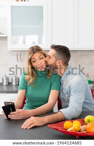 Blonde woman takes a selfie while being kissed by her boyfriend.
Girl with green shirt photographs herself for social media. Happy couple post their love on the internet. Social addiction.