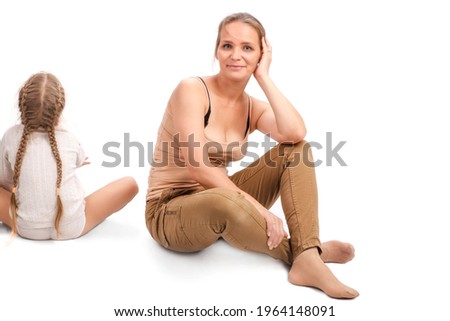Mom and daughter are sitting on the floor in a white room