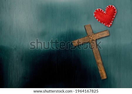 Red heart with a wooden crucifix on a desk. Concept Jesus loves you,