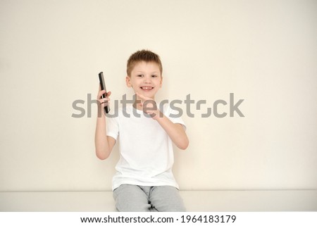 The happy smiling boy received a phone as a gift. Internet addiction. Childhood, cyberbullying and communication concept. White background. Space for text