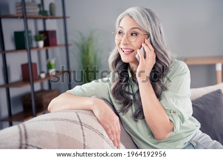 Photo portrait of old lady sitting on sofa talking on cellphone smiling happy