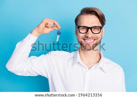 Photo of happy cheerful young man realtor hold keys new house relocation isolated on blue color background