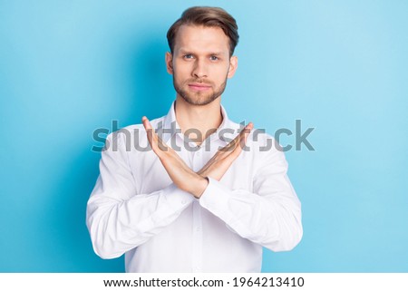 Portrait of attractive serious guy showing stop sign crossed hands isolated over bright blue color background