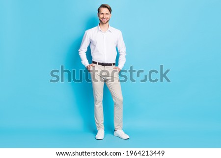 Full length photo of attractive young man smile hold hands pockets smile good mood worker isolated on blue color background