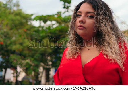 Plus size woman in the park. Portrait of beautiful large lady. Portrait of a serious Hispanic woman outdoors.