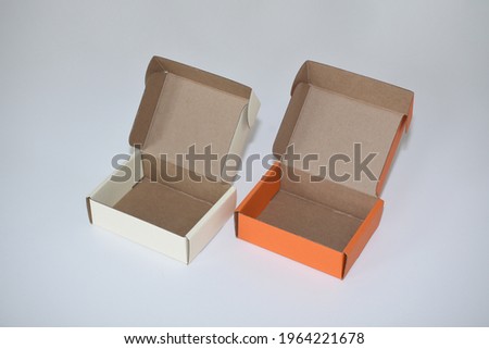 Two orange and beige cardboard boxes with open lids on a white background