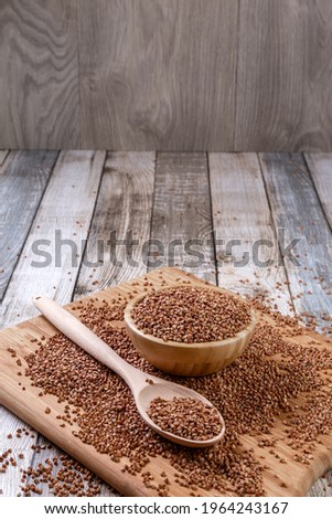 Scattered buckwheat. Buckwheat in a wooden bowl and spoon lies on a wooden table. Scattered buckwheat. Healthy eating. Diet food. Copy space. Close-up. High quality photo