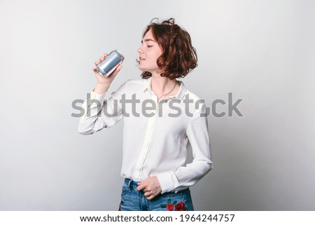 A young woman with a tin can, a metal soda can, or a beer can in front. cylindrical aluminum cans, bottles of cold drinks, a woman holding a metal can. Royalty-Free Stock Photo #1964244757