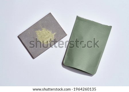 Dry cosmetological clay beside zip packet lying on white background, flat lay, top view. Beauty treatment products concept
