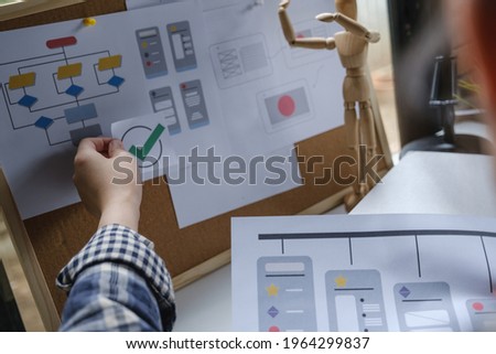 Rear view of developer ux and ui designer about mobile phone app and making flow chart at the board. Creative digital development agency concept.