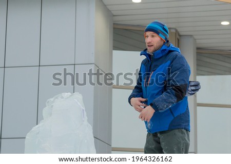 Sculptor on the scaffolding against the background of the ice block el