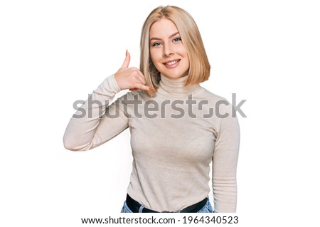 Young blonde woman wearing casual clothes smiling doing phone gesture with hand and fingers like talking on the telephone. communicating concepts. 