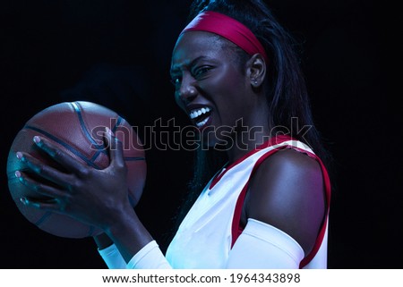 Wild. Beautiful african-american female basketball player in motion and action in neon light on black background. Concept of healthy lifestyle, professional sport, hobby. Woman in sport.