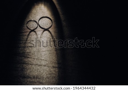 Close-up of two gold wedding rings on a black background.