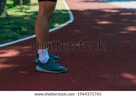 Close-up photo of male running shoes on a race track in the park