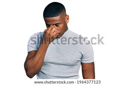 Young black man wearing casual t shirt tired rubbing nose and eyes feeling fatigue and headache. stress and frustration concept. 