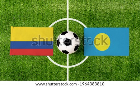Top view ball with Colombia vs. Palau flags match on green football field.