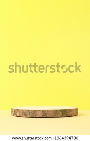 Round wooden podium on beige and yellow background for product presentation. Front view. Copy space. Vertical