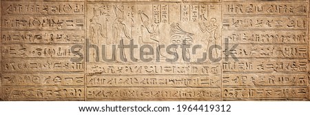 Old Egyptian hieroglyphs on an ancient background. Wide historical background. Ancient Egyptian hieroglyphs as a symbol of the history of the Earth.  Royalty-Free Stock Photo #1964419312